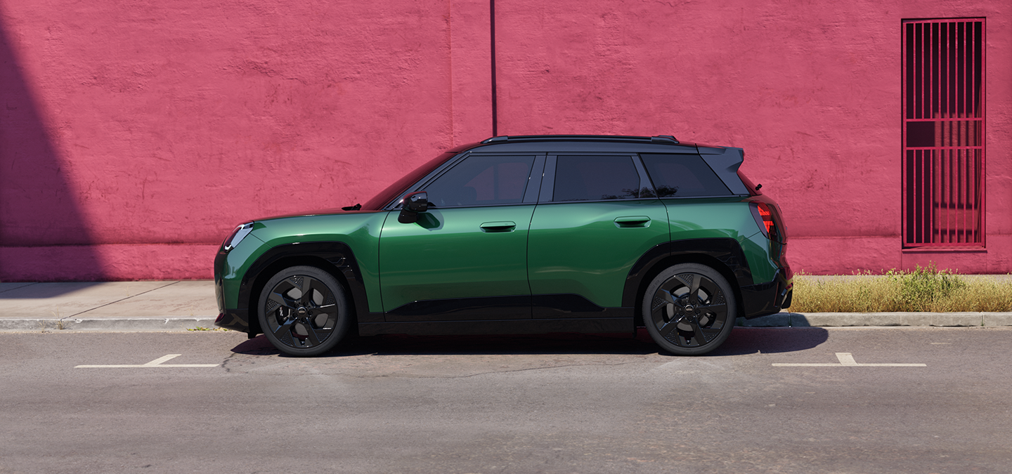 מבט צדדי על ה-MINI Aceman החשמלית בצבע ירוק British Racing Green וגג שחור ברחוב.