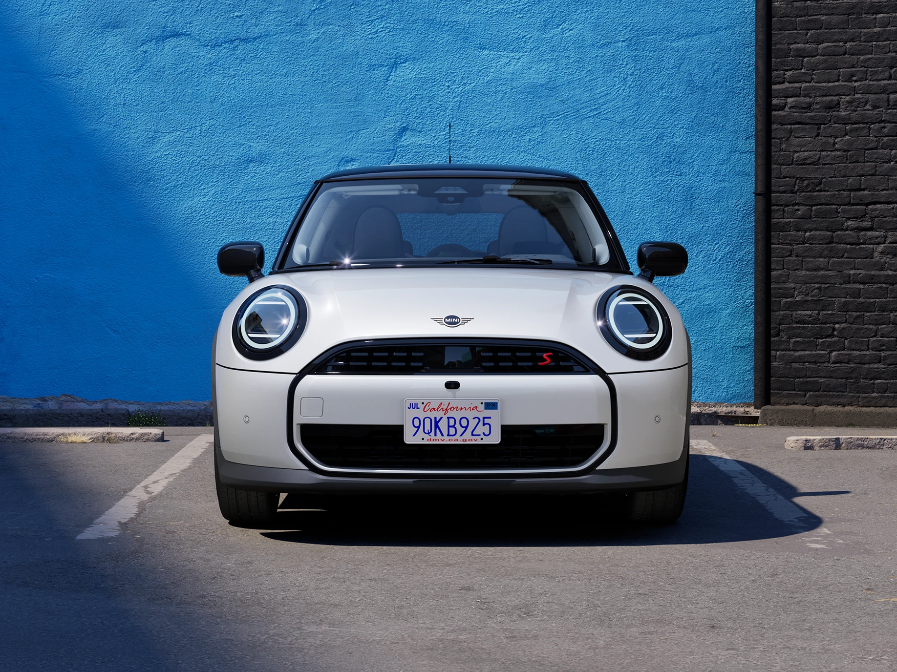 מבט קדמי על ה-MINI Cooper‏ בצבע לבן Nanuq White וגג שחור בחניה.