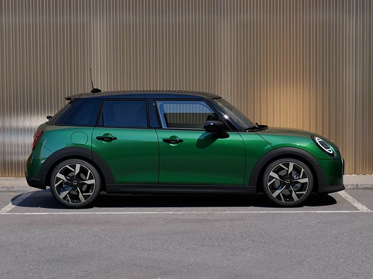 מבט צדדי על ה-MINI Cooper‏ 5 דלתות בצבע ירוק British Racing Green וגג שחור בחניה.