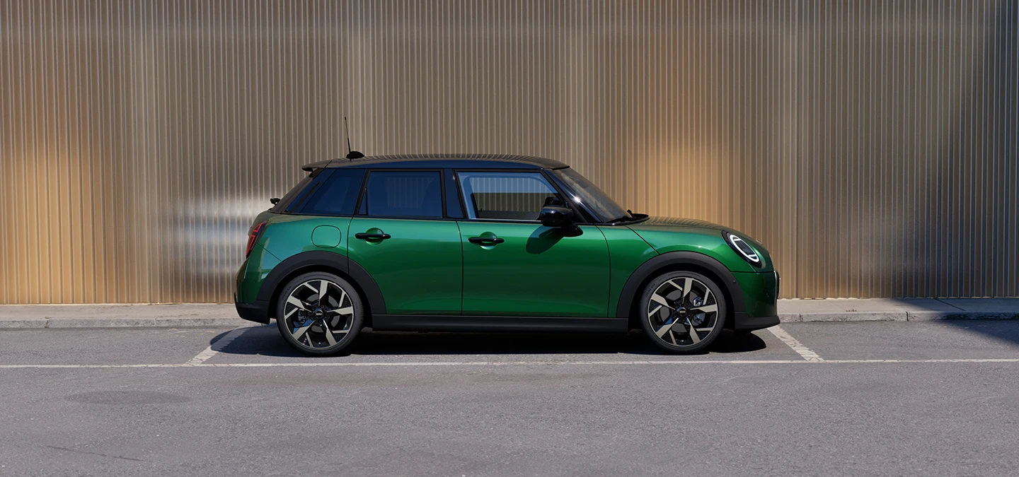 מבט צדדי על ה-MINI Cooper‏ 5 דלתות בצבע ירוק British Racing Green וגג שחור בחניה.