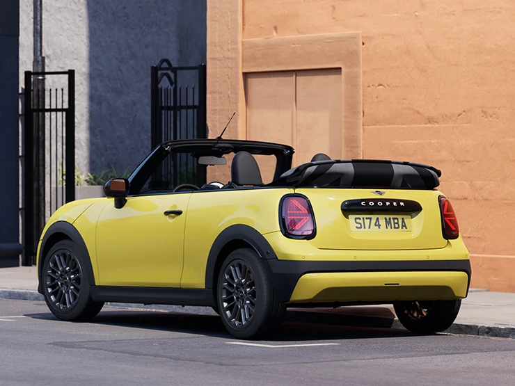 מבט אחורי מצד שמאל של ה-MINI Cooper‏ קבריולה בצבע צהוב Sunnyside Yellow בחניה.