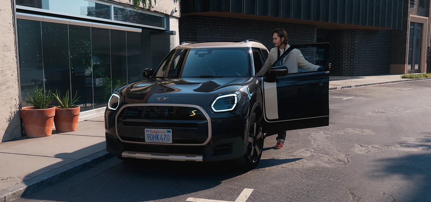 מבט קדמי על ה-MINI Countryman החשמלית בצבע שחור Midnight Black וגג בצבע כסף Vibrant Silver ברחוב.