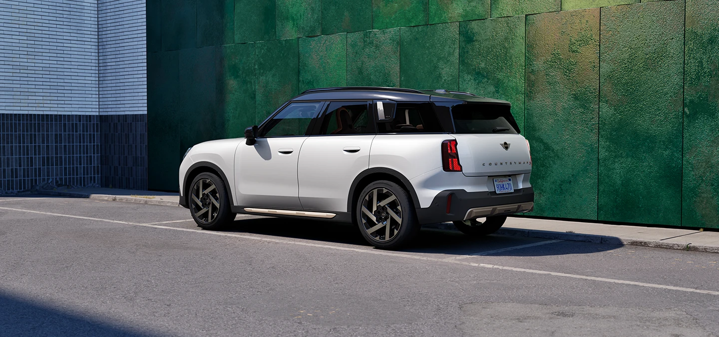 מבט אחורי מהצד של ה-MINI Countryman בצבע לבן Nanuq White וגג שחור עומד ברחוב.